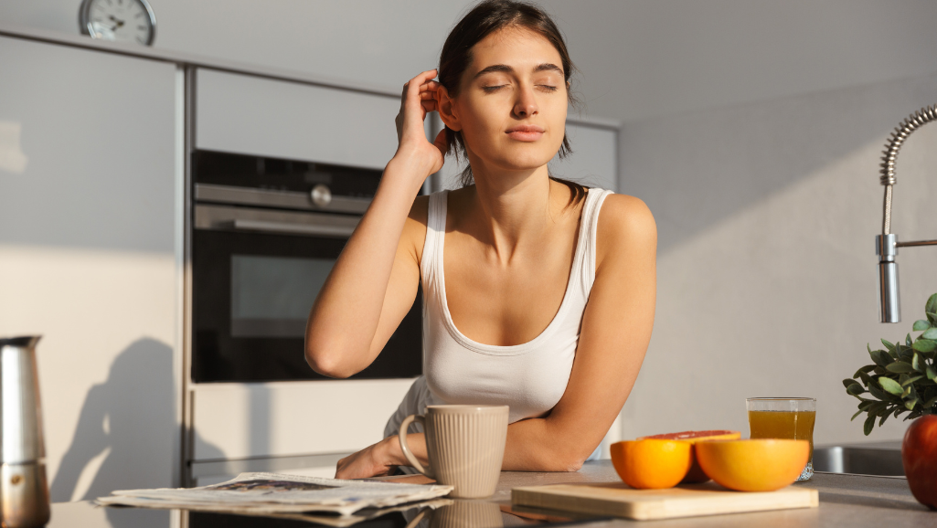 A peaceful, organized daily routine structure illustrated in a serene, minimalist home. In the foreground, a desk with a laptop, planner, and a cup of tea, illuminated by warm natural lighting from large windows. The middle ground features a comfortable armchair and a simple bookshelf, while the background showcases a tranquil plant-filled corner. The overall mood is one of calm focus and balanced productivity, encouraging the viewer to establish a routine that supports their well-being and unlocks their potential.