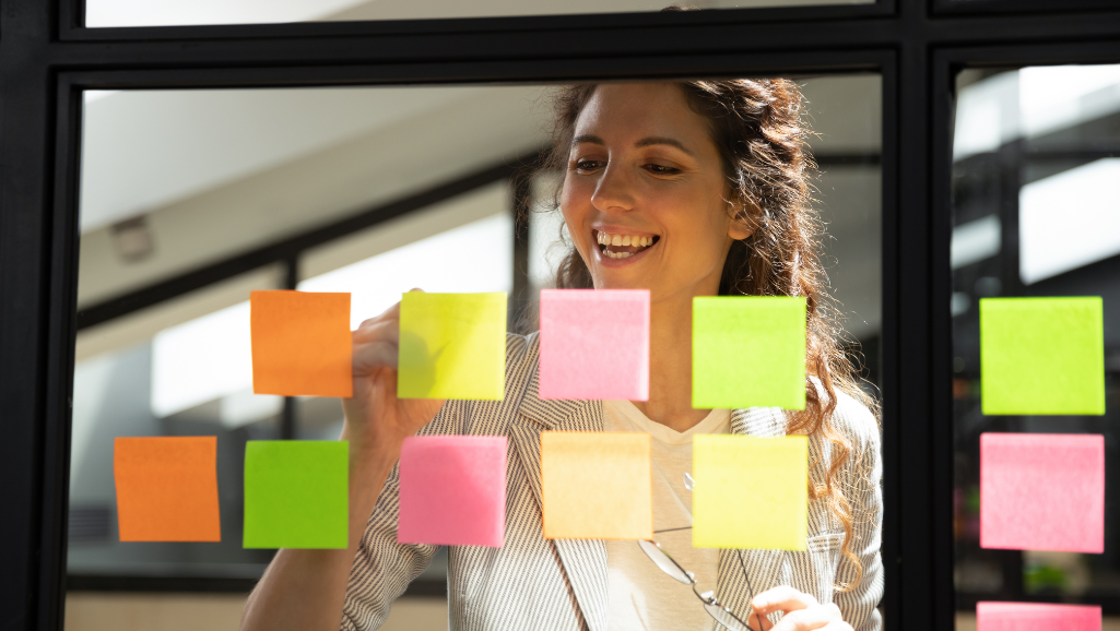 A sleek, minimalist workspace with an organized system of sticky notes, task lists, and digital tools. The foreground features a clean, wooden desk with a laptop, pen holder, and a stylized habit tracker on the screen. The middle ground showcases a corkboard adorned with neatly arranged notes and reminders, illuminated by a soft, indirect light. The background depicts a serene, minimalist environment with a large window overlooking a calming landscape, creating a sense of focus and productivity. The overall mood is one of efficiency, clarity, and a well-designed personal habit system.
