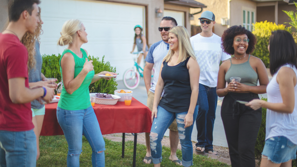 A vibrant, sun-drenched outdoor scene, with lush greenery and colorful flowers in the foreground. In the middle ground, a group of friends laughing and chatting while sipping on refreshing beverages. In the background, a serene, calming body of water reflects the warm tones of the sky. The overall atmosphere is one of positivity, comfort, and inspiration - a haven of camaraderie and rejuvenation. The lighting is soft and natural, enhancing the tranquil mood. The camera angle is slightly elevated, capturing the full scope of the uplifting environment.